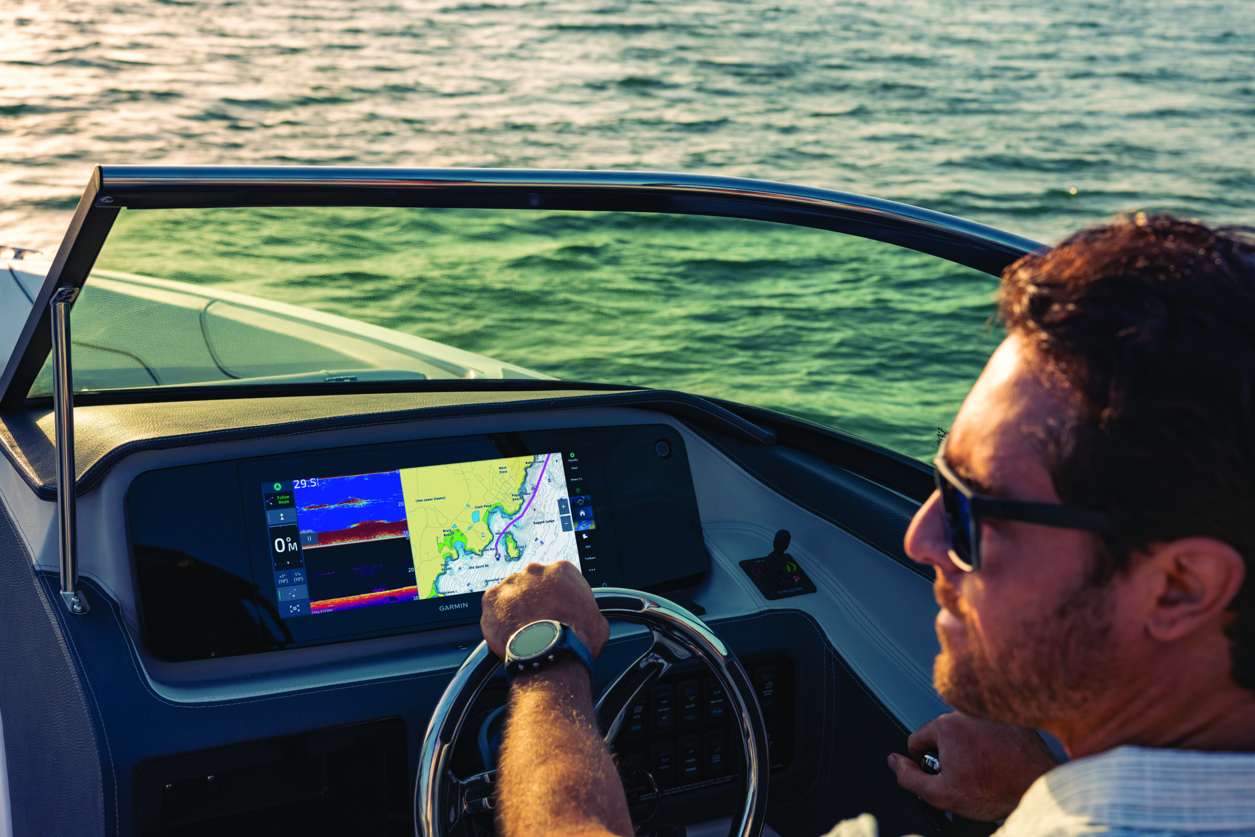 Un homme conduit un bateau avec ses écrans de navigation Garmin Marine